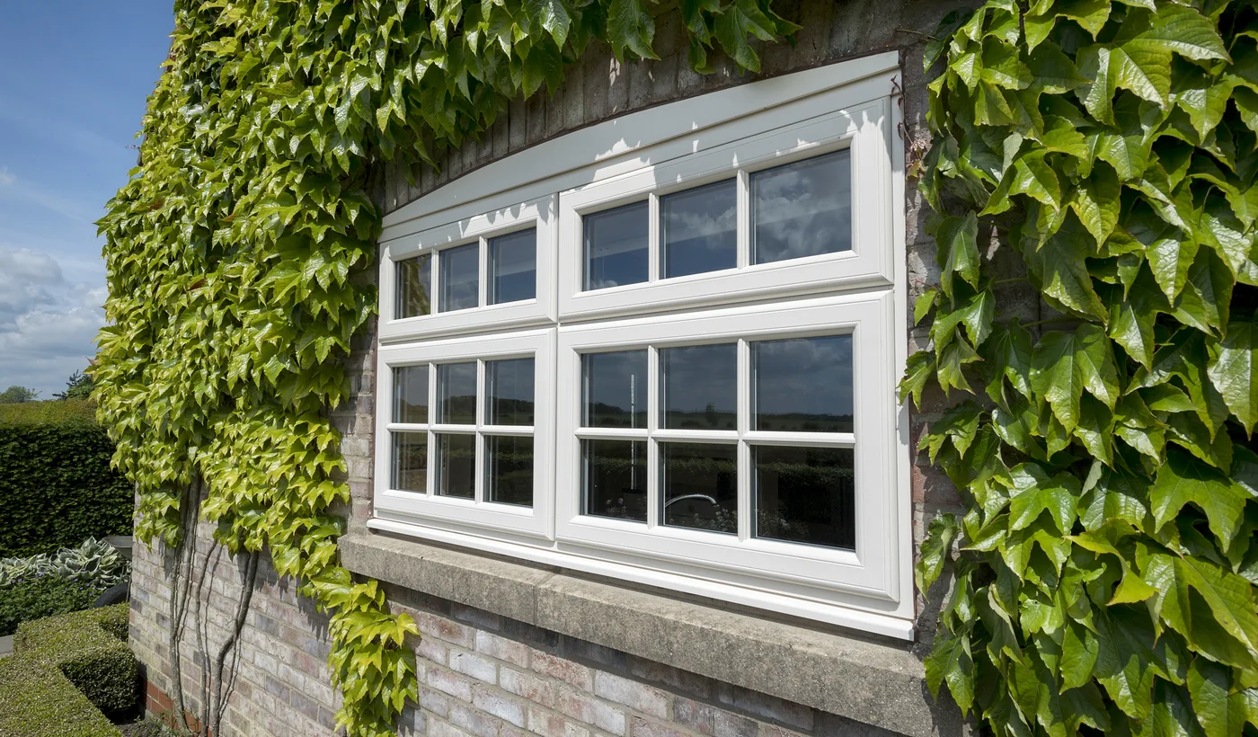 White uPVC casement windows on an ivy covered wall