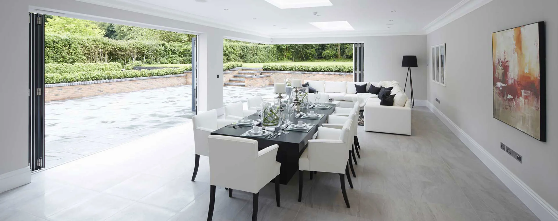 Open plan dining room with wide aluminium bifold doors opening onto a garden