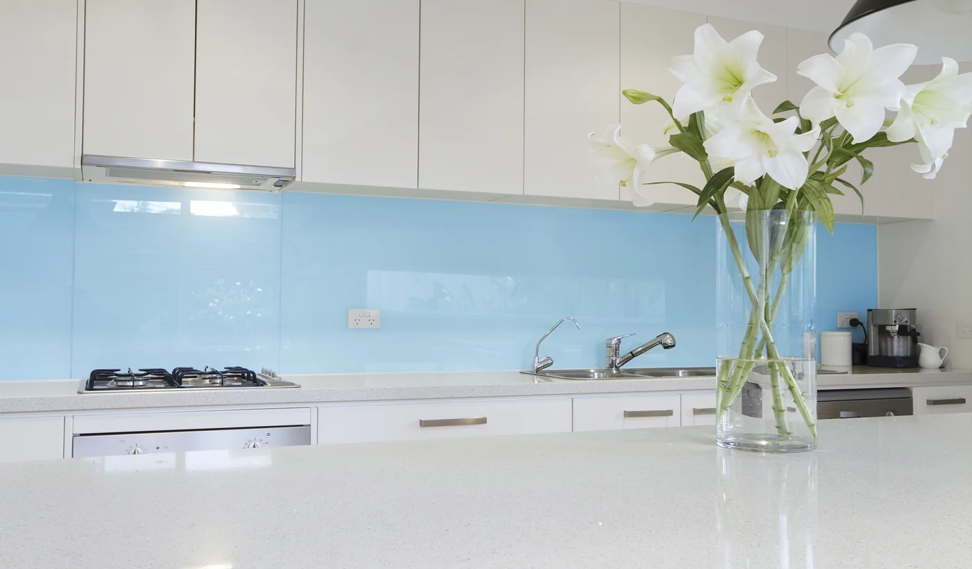 Blue coloured glass splashback in a white kitchen